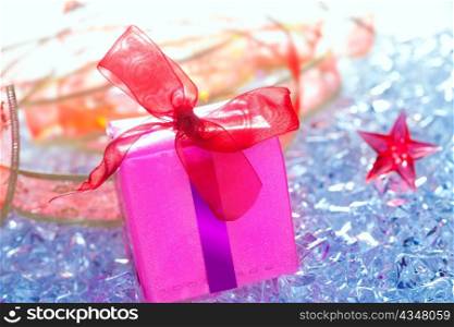 christmas pink gift box with ribbon on winter ice and stars