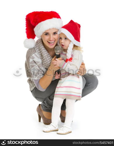 Christmas portrait of happy mother and baby girl singing into microphone