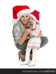 Christmas portrait of happy mother and baby girl singing into microphone