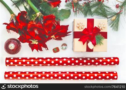 Christmas preparation: wrapping paper, gift, amaryllis and winter decoration. Christmas mood on white background. Top view