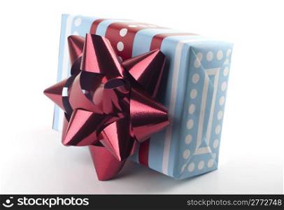 Christmas present wrapped in blue, red and white wrapping paper with big red bow isolated on white background.