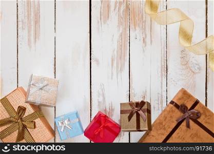 Christmas presents and golden ribbon over a rustic wooden table seen from above. Christmas presents and golden ribbon over a rustic wooden table