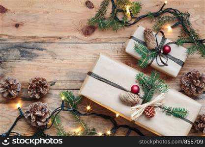 Christmas presents under a Christmas tree. Gifts wrapped in paper decorated with cones and pine twigs put on wooden floor. View from above. Copy space for text at top of image