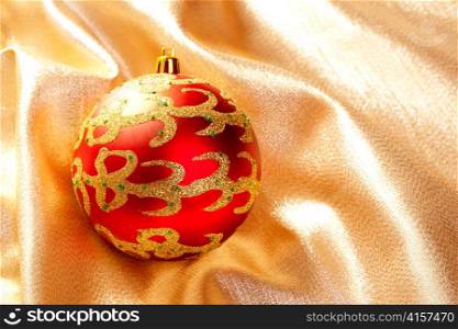 Christmas red bauble on golden fabric background