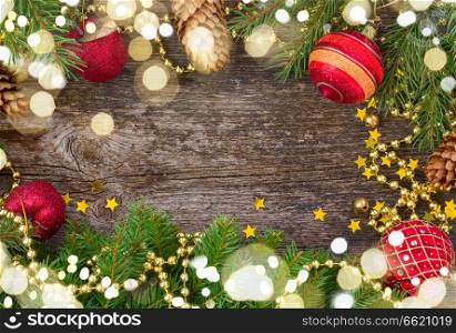 christmas red decorations and fir tree frame on wooden background with light beams. christmas frame with light beams