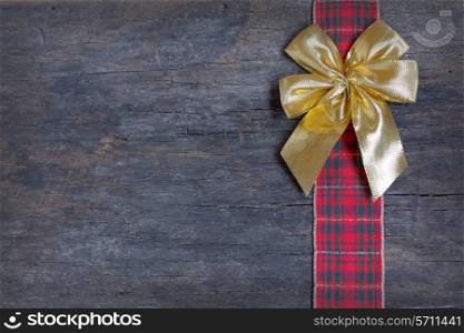 Christmas ribbon and golden gift bow isolated on old wooden background