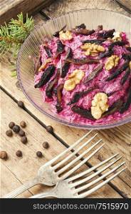 Christmas salad with beets, prunes and nuts.Beet salad in retro wooden tray. Prune beet salad
