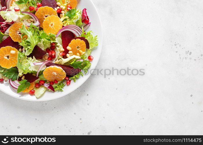 Christmas salad with boiled beet, red onion, tangerines, pomegranate, parsley, pine nuts and lettuce leaves