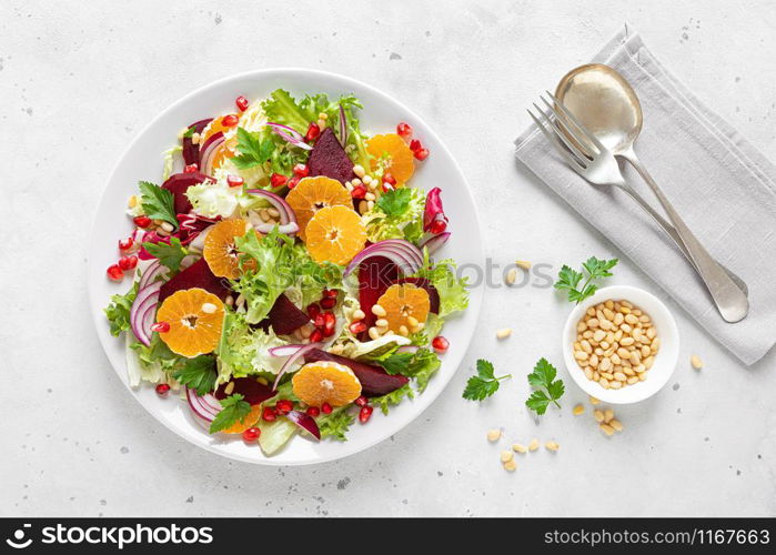 Christmas salad with boiled beet, red onion, tangerines, pomegranate, parsley, pine nuts and lettuce leaves