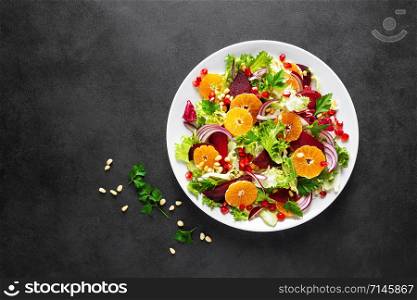 Christmas salad with boiled beet, red onion, tangerines, pomegranate, parsley, pine nuts and lettuce leaves