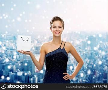 christmas, sale, advertisement, holydays and people concept - smiling woman with white blank shopping bag over snowy city background