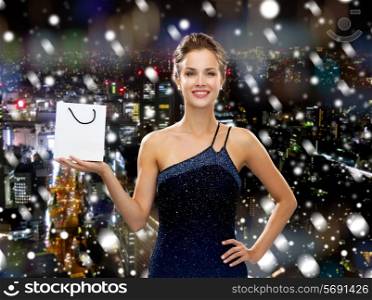 christmas, sale, advertisement, holydays and people concept - smiling woman with white blank shopping bag over snowy night city background