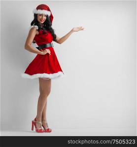 Christmas santa girl point hand, happy smile woman wear new year party Santa Clause costume show side empty copy space, white background. Christmas santa girl point hand