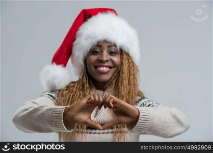 Christmas Santa hat woman portrait. Smiling happy girl on gray background showing love gesture