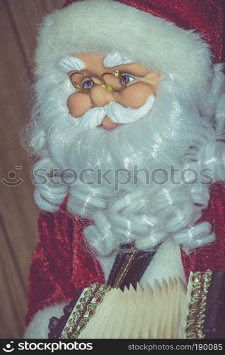 Christmas santa toy playing the accordion, vintage photo effect background.