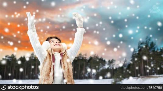 christmas, season and happiness concept - happy little girl enjoying snow over winter forest background. happy little girl enjoying winter and snow