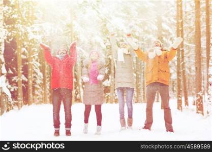 christmas, season, friendship and people concept - group of happy men and women having fun and playing with snow in winter forest