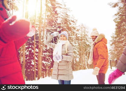 christmas, season, friendship and people concept - group of smiling men and women having fun and playing snowball game in winter forest