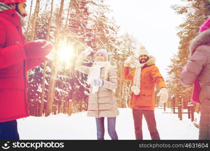 christmas, season, friendship and people concept - group of smiling men and women having fun and playing snowball game in winter forest