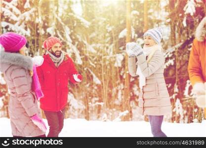christmas, season, friendship and people concept - group of smiling men and women having fun and playing snowball game in winter forest