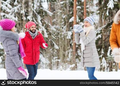 christmas, season, friendship and people concept - group of smiling men and women having fun and playing snowball game in winter forest