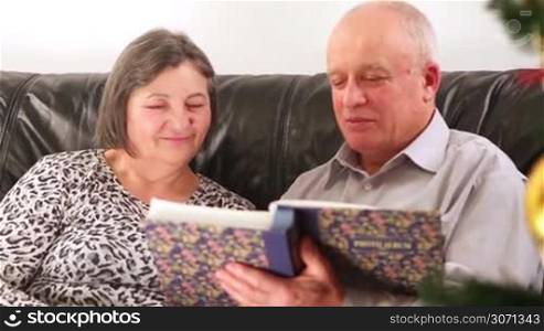 Christmas - senior couple going through photo album at Holiday time.