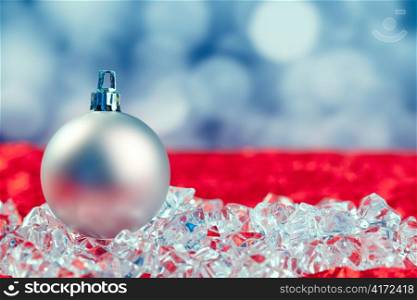 Christmas silver bauble on ice cubes with blue lights bokeh background