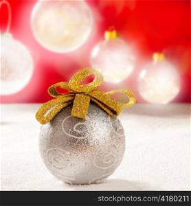 Christmas silver bauble with golden loop on snow red background