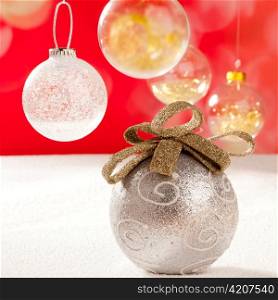 Christmas silver bauble with golden loop on snow red background