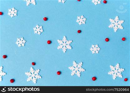 christmas, snow and winter holidays concept - white snowflake decorations and red berries on blue background. white snowflakes and berries on blue background