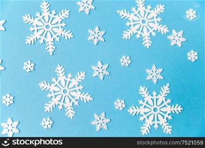 christmas, snow and winter holidays concept - white snowflake decorations on blue background. white snowflake decorations on blue background