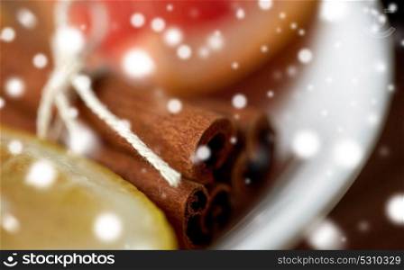 christmas, spice and ethnoscience concept - close up of cinnamon on plate over snow. close up of cinnamon on plate