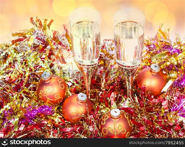 Christmas still life - above view of two glasses of champagne at golden Xmas decorations with blurred Christmas lights background