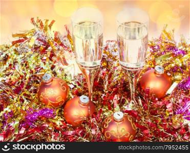 Christmas still life - above view of two glasses of champagne at golden Xmas decorations with blurred Christmas lights background