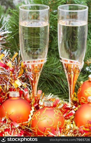 Christmas still life - golden Xmas baubles and tinsel and two glasses of sparkling wine on Christmas tree background