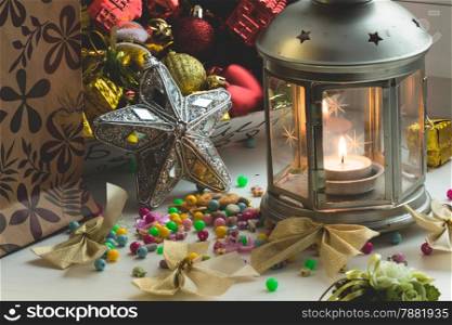 Christmas still life: lantern with burning candle and New Year tree decorations. Aperture 16