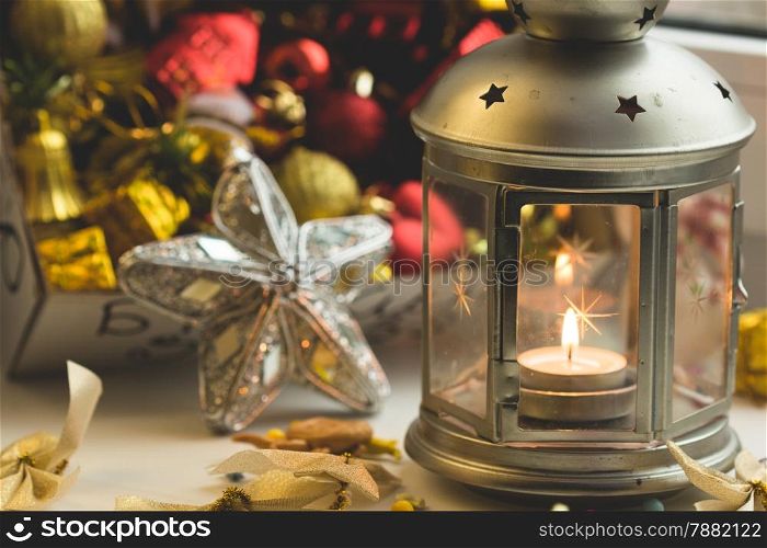 Christmas still life: lantern with burning candle and New Year tree decorations. Aperture 4