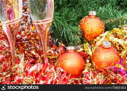 Christmas still life - Two glasses of champagne with golden Xmas decorations close up on Christmas tree background