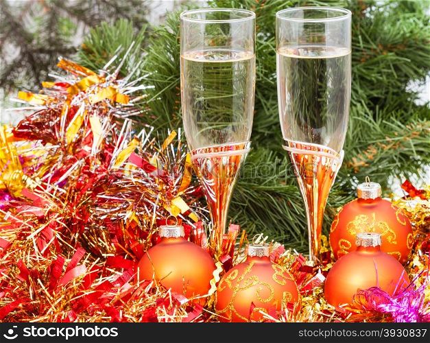 Christmas still life - Two glasses of champagne with golden Xmas decorations on Christmas tree background