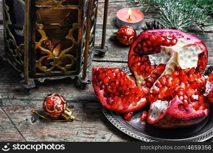 Christmas still life with an Oriental lantern with candle and the broken pomegranate. Arabic candle holder and pomegranate