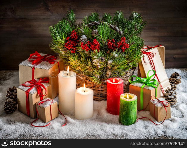 Christmas still life with burning candles and gift box. Christmas tree branches in basket. Vintage style toned picture with light effects