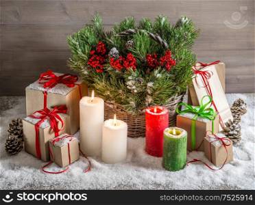 Christmas still life with burning candles and gift box. Festive decoration. Christmas tree branches in basket