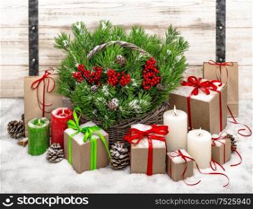 Christmas still life with burning candles and gift box. Festive decoration. Christmas tree branches in basket