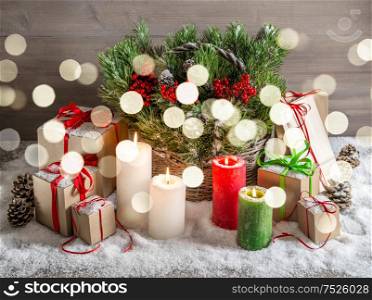 Christmas still life with burning candles and gift box. Festive decoration. Vintage style tones picture with lights effect