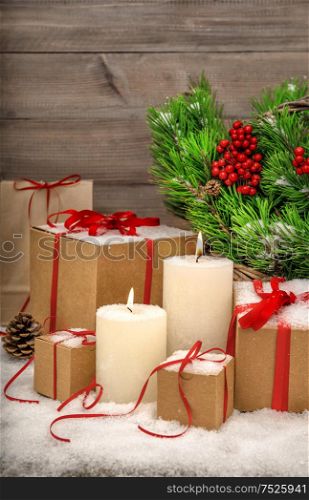 Christmas still life with burning candles, gift boxes and christmas tree branches in basket. Vibrant colors