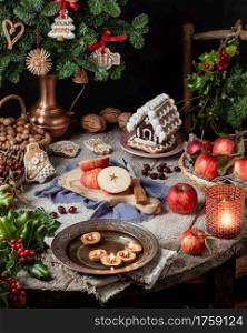 Christmas still life with candles made from nut shells floating in a bowl of water, gingerbread cookies and apples