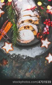 Christmas stollen with spices , fir branches and red holiday decoration, close up, place fot text