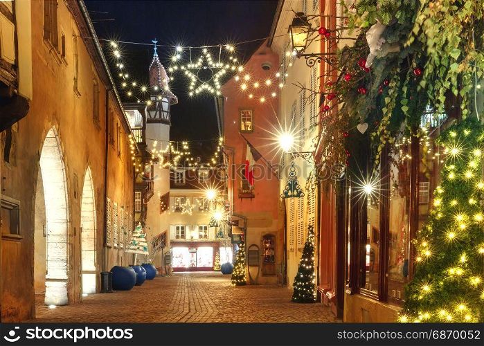 Christmas street at night in Colmar, Alsace, France. Traditional Alsatian half-timbered houses in old town of Colmar, decorated and illuminated at christmas time, Alsace, France