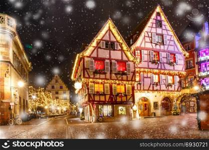 Christmas street at night in Colmar, Alsace, France. Traditional Alsatian half-timbered houses in old town of Colmar, decorated and illuminated at snowy christmas night, Alsace, France