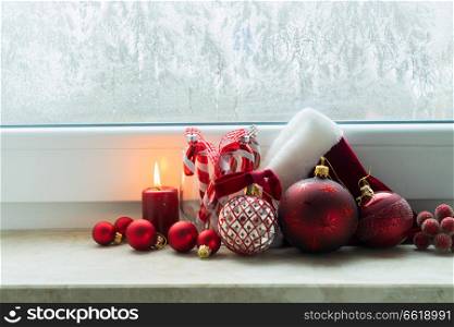 Christmas styled scene with glowing candle and christmas decorations on winter windowsill. Christmas scene with burning light
